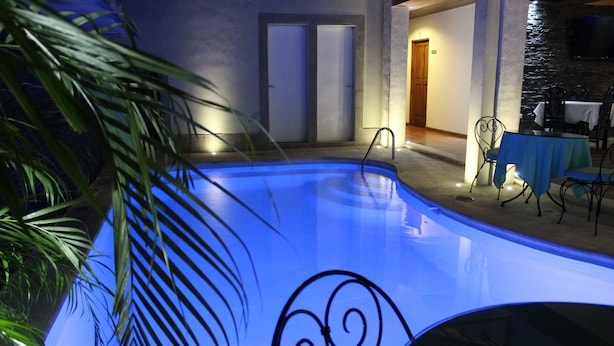 Ein Schwimmbecken mit ornamentalem Design, umgeben von einer Terrasse mit Sitzgelegenheiten im Freien.