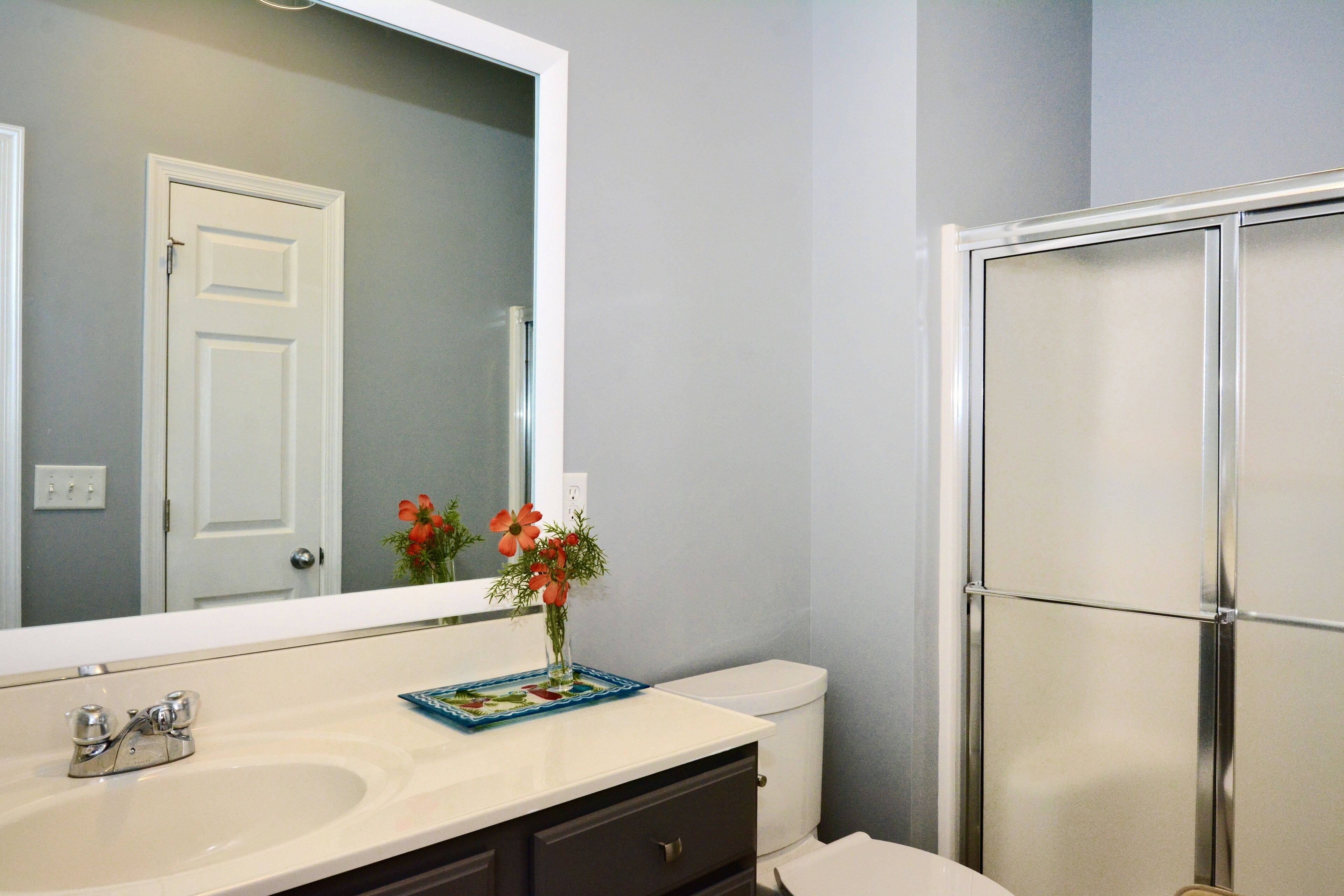A bathroom with a white sink, a mirror, a toilet, and a shower enclosure.