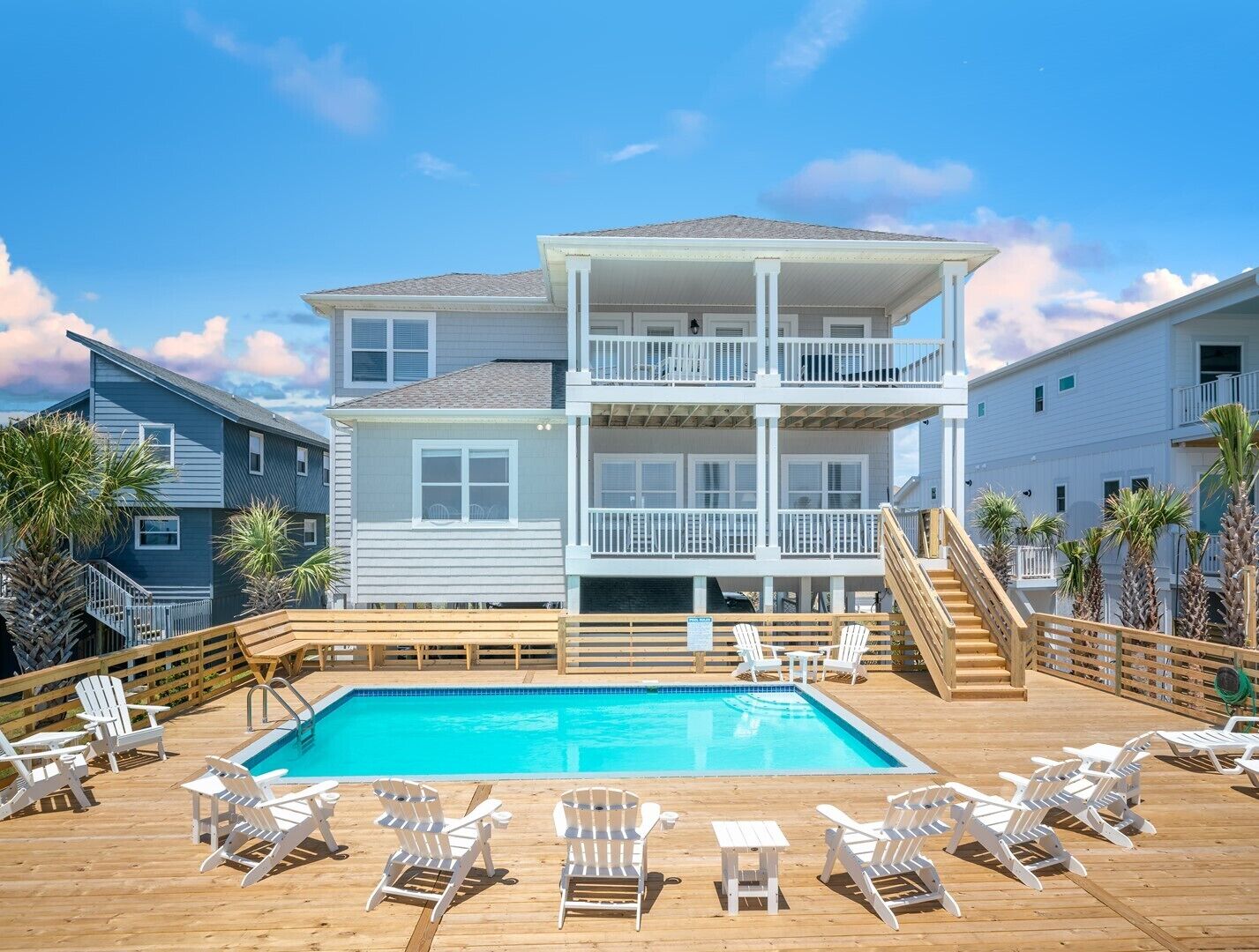 Un edificio de dos pisos con piscina y sillas de deck.