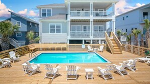 Un edificio de dos pisos con piscina y sillas de deck.