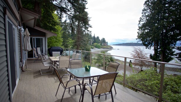 A deck with a table and chairs, overlooking a body of water and forested area. - Comfortable luxury suite with epics views, on the Beach, Sunshine Coast (Halfmoon Bay)