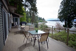 A deck with a table and chairs, overlooking a body of water and forested area. - Comfortable luxury suite with epics views, on the Beach, Sunshine Coast (Halfmoon Bay)