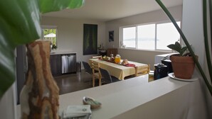 A modern kitchen with a dining area, large windows, and potted plants. - Comfortable luxury suite with epics views, on the Beach, Sunshine Coast (Halfmoon Bay)