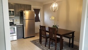 A kitchen with a refrigerator, oven, and microwave. There is a dining table with chairs and a chandelier above. - Cozy 3 Bedroom Ranch No steps (Tiffin)