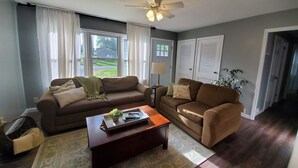A living room with two couches, a coffee table, a lamp, and a ceiling fan. - Cozy 3 Bedroom Ranch No steps (Tiffin)