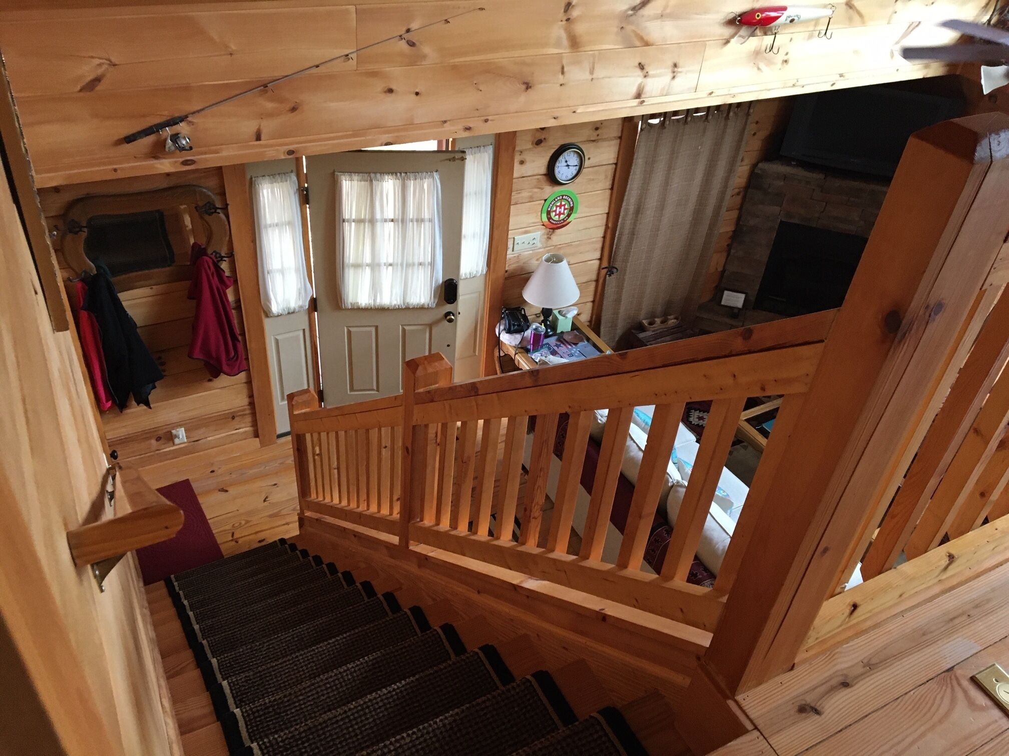 L’intérieur d’un chalet en bois, avec un escalier, des murs en bois et une porte avec des rideaux.