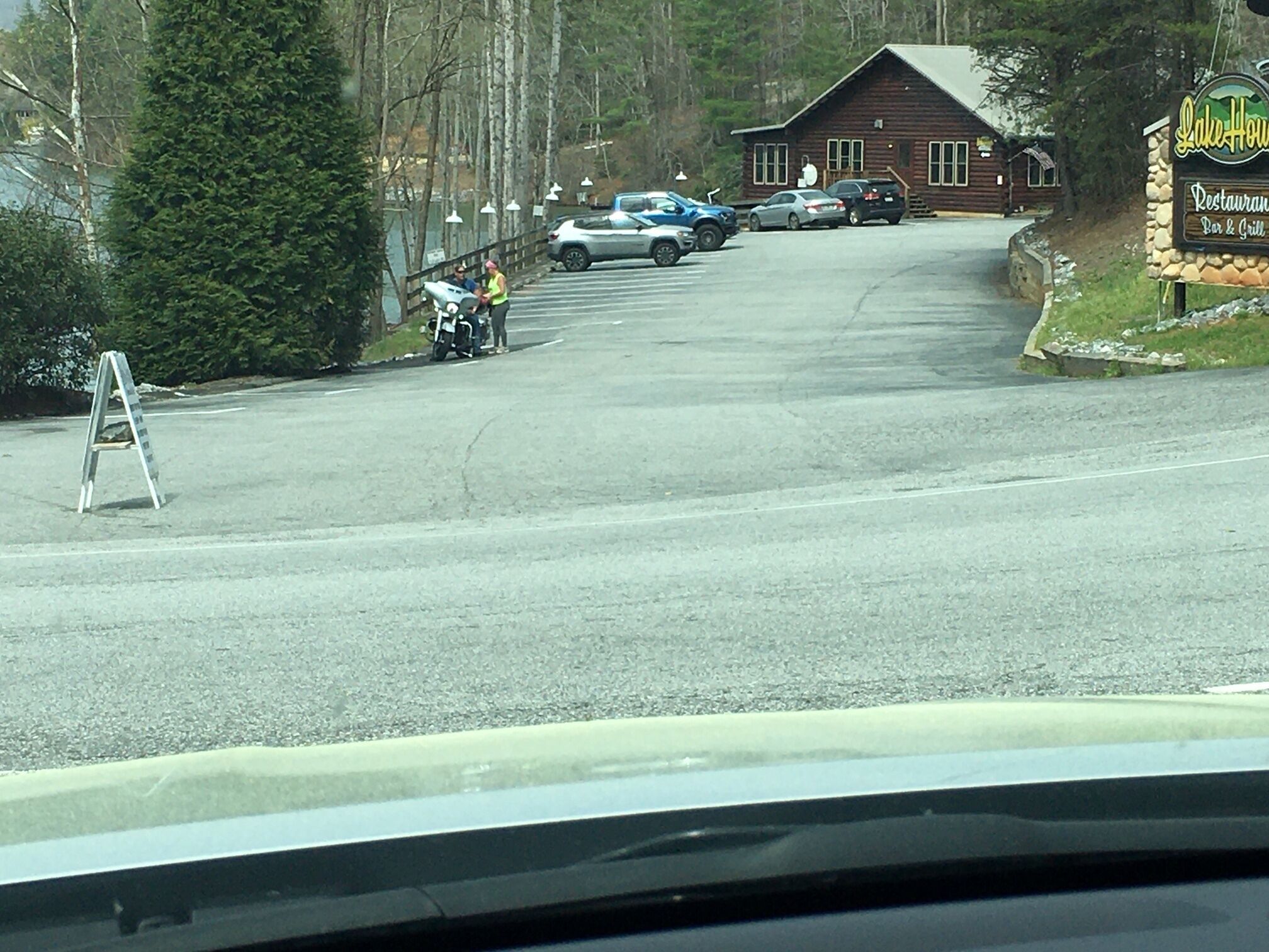 Een weg naar een gebouw in chaletstijl, met een bord voor restaurant, bar en grill.