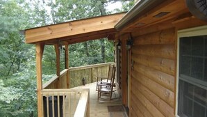 Une terrasse en bois avec une chaise berçante, une fenêtre et une porte.