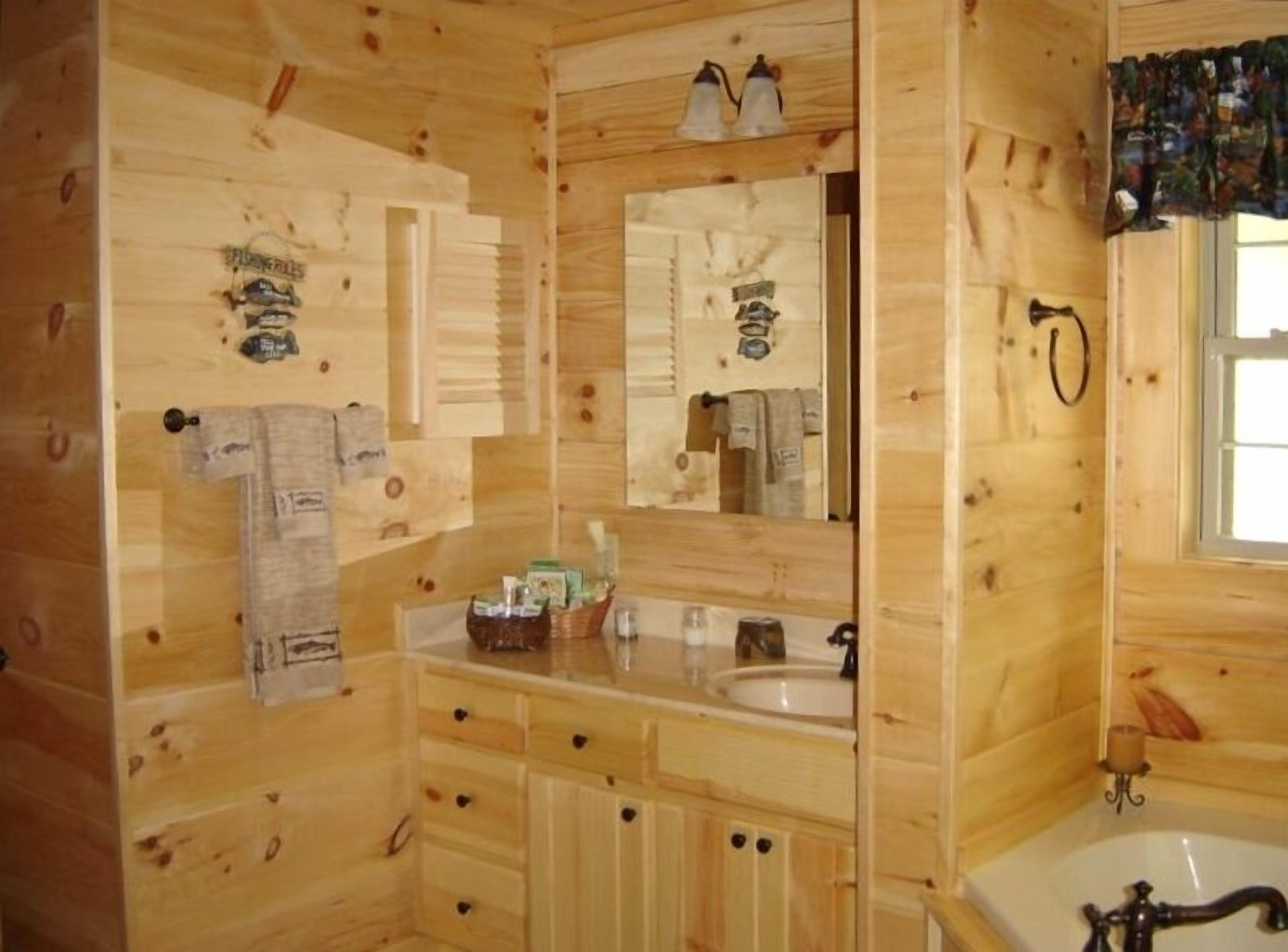 A wooden cabin bathroom with a sink, mirror, and two lights above it.