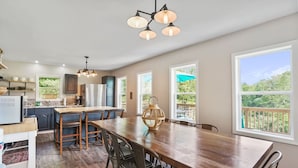 A spacious kitchen with a large wooden table, bar stools, and a hanging light fixture. - ONE OF A KIND HISTORIC LOG CABIN ON 10+ ACRES IN HOCKING HILLS (Sugar Grove)