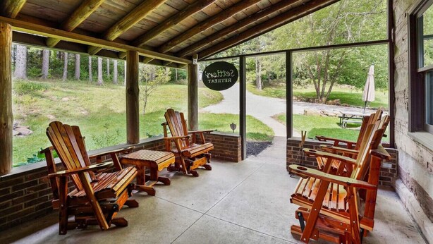 A covered outdoor seating area with Adirondack chairs and a sign reading "Ski Chalet." - ONE OF A KIND HISTORIC LOG CABIN ON 10+ ACRES IN HOCKING HILLS (Sugar Grove)