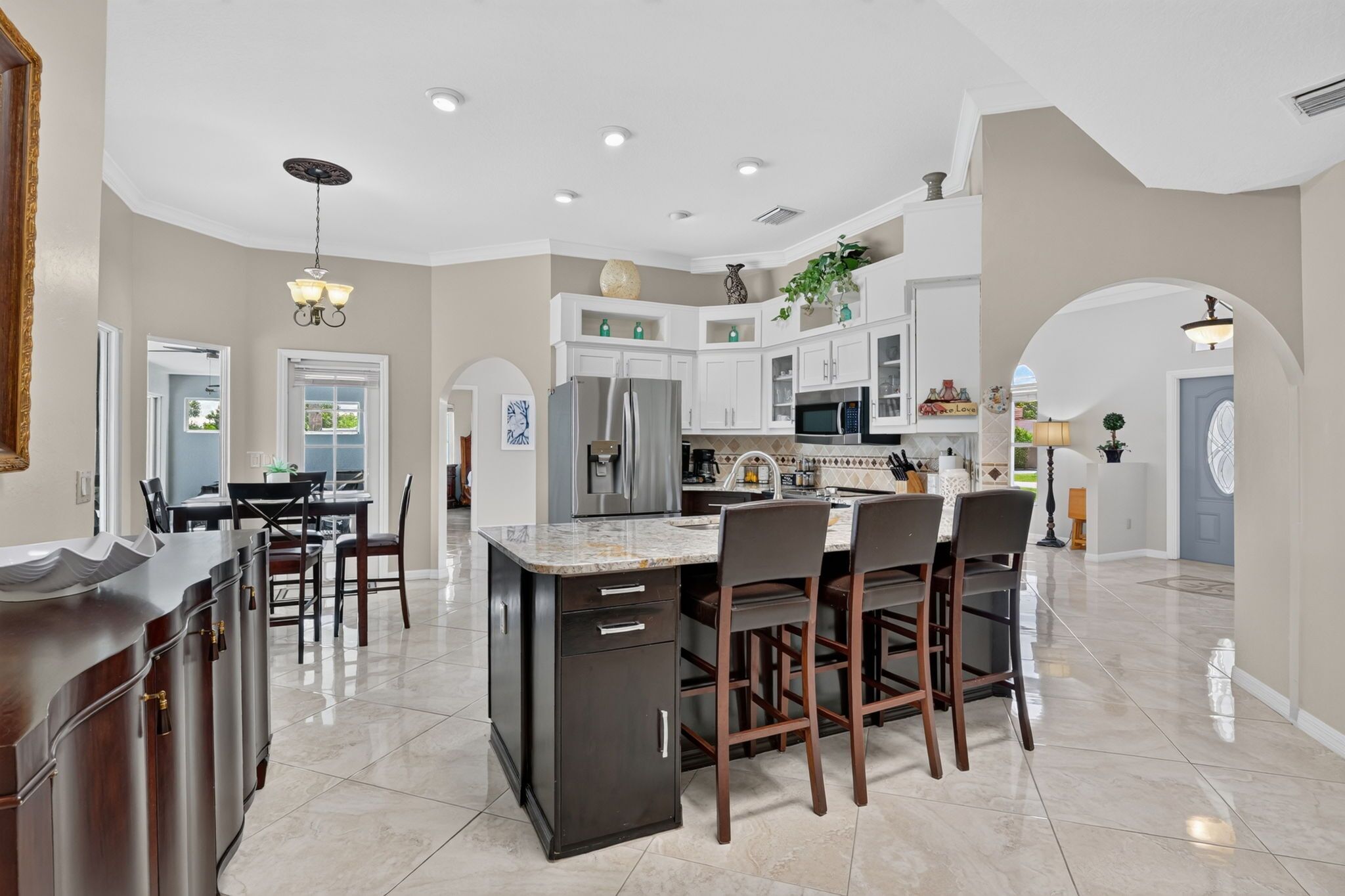 A spacious kitchen with a central island, dark cabinetry, and a dining area with chairs.