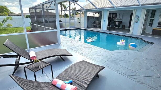 An outdoor swimming pool with lounge chairs and a covered patio area. - Paradise Palace and POOL home (Cape Coral)