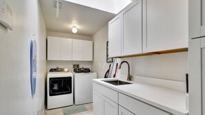A compact kitchen with white cabinets, a built-in oven, a sink, and a skylight. - Paradise Palace and POOL home (Cape Coral)