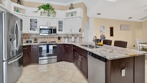 A modern kitchen with white cabinetry, stainless appliances, and a marble countertop. - Paradise Palace and POOL home (Cape Coral)