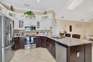 A modern kitchen with white cabinetry, stainless appliances, and a marble countertop. - Paradise Palace and POOL home (Cape Coral)