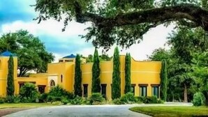 A yellow building with a central courtyard, surrounded by greenery and trees. - Blanco Rapids Ranch (Wimberley)