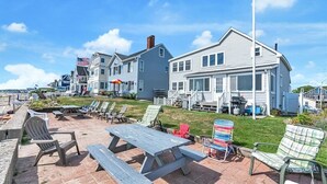 A beachfront property with a patio area featuring outdoor seating and a picnic table. - Enjoy sunrises on the Private Beach - 4 bedrooms (Wells)