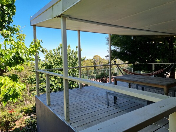 A covered outdoor area with a hammock, a bench, and a view of trees and greenery. - Sunset Hues-Enjoy Peace & Nature in lovely Adelaide Hills overlooking Adelaide (Norton Summit)