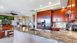 Una cocina moderna con encimeras de granito, electrodomésticos de acero inoxidable y armarios de madera.