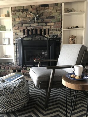Cozy living room with a fireplace, armchair, and small table.