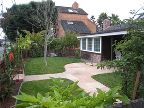 Enjoy a serene outdoor space with a beautifully maintained lawn, patio, and lush plants.