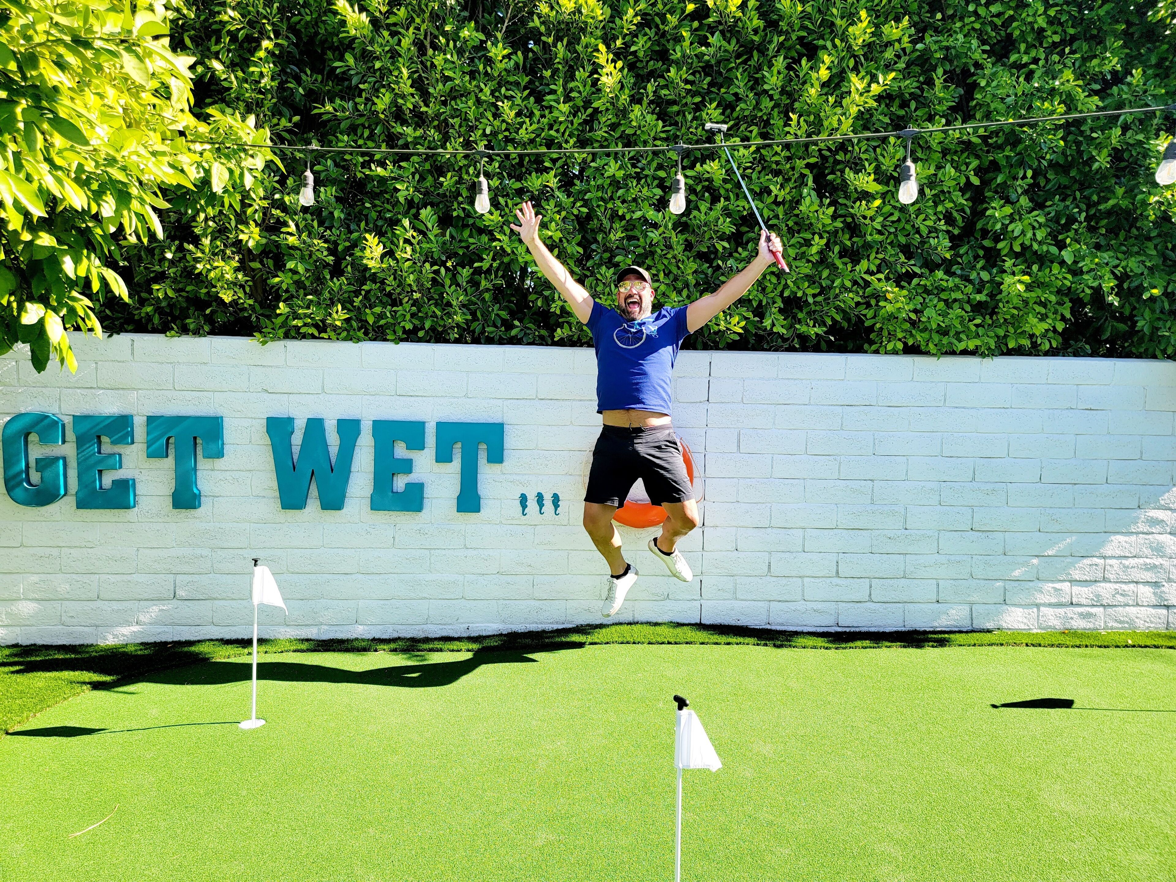 Una persona salta di fronte a un muro con la scritta "GET WET".