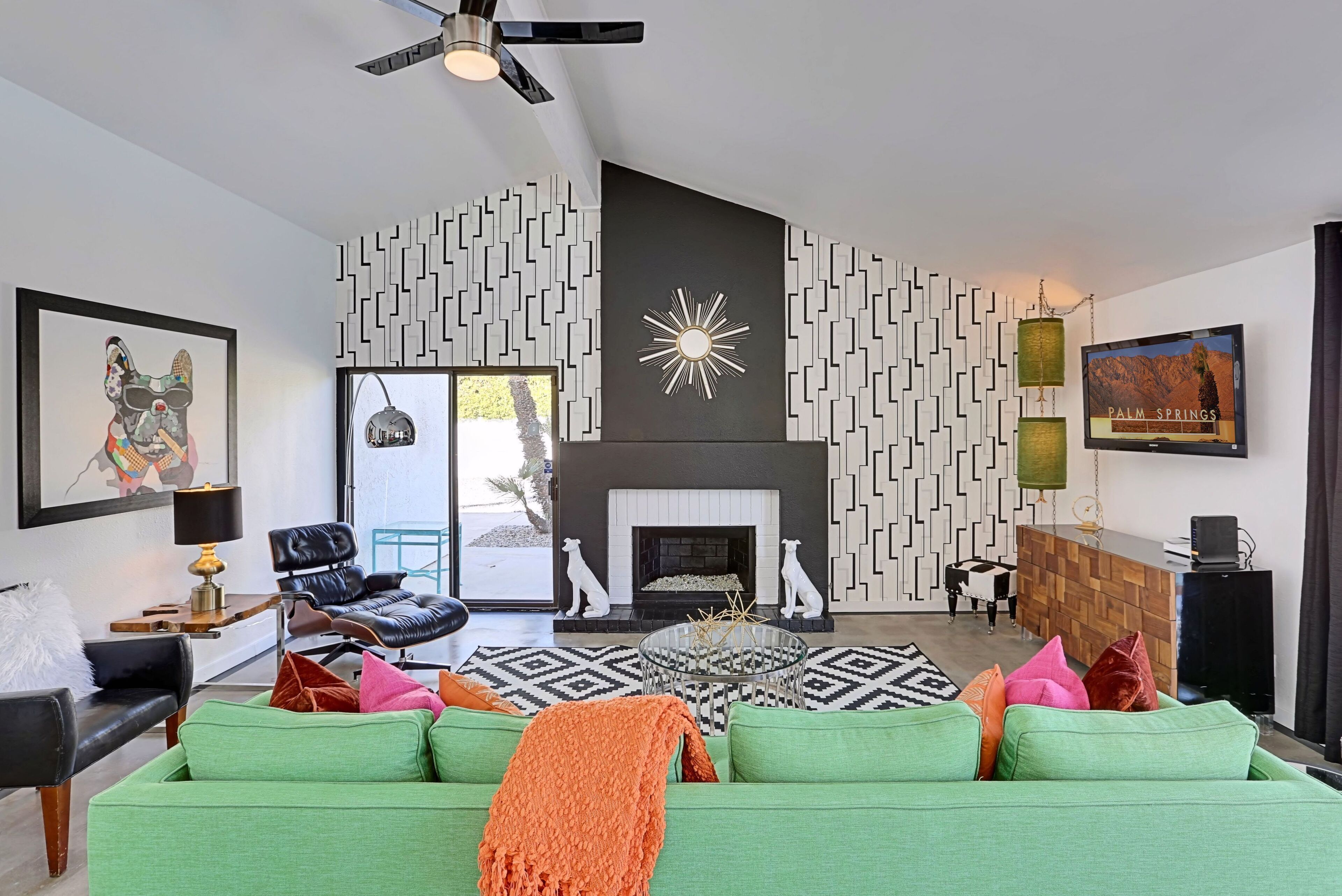 A modern living room with a green sofa, a fireplace, and a patterned wall.