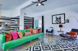 Un salon moderne avec un canapé vert, un tapis à motifs noir et blanc et une table basse en verre.