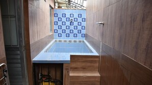 A narrow hallway with a blue-tiled wall and a wooden bench. - Cozy house with Wi-Fi and air conditioning. (Tamandaré)