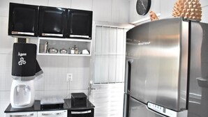 A modern kitchen with a stainless steel refrigerator, a coffee machine, and black cabinets. - Cozy house with Wi-Fi and air conditioning. (Tamandaré)