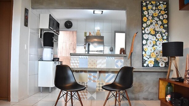 A modern kitchen with white cabinets, a stainless steel refrigerator, and a patterned backsplash. There are two black chairs in front of the counter. - Cozy house with Wi-Fi and air conditioning. (Tamandaré)