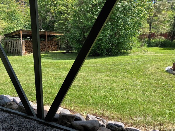 A well-maintained grassy area with a wooden structure and a stone wall. - A Private, Cozy Cabin Near Bigfork for Two with a Clawfoot Tub (Bigfork)
