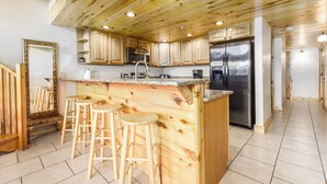 Eine Küche mit Holzausstattung, einem Edelstahlkühlschrank, einer Spüle und Barhocker.