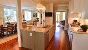 A modern kitchen with a central island, built-in appliances, and a dining area with chairs and a table. - The Brigham 5 Star! ROOFTOP TERRACE Historic Savannah ULTIMATE LUX VACATION!! (Savannah)