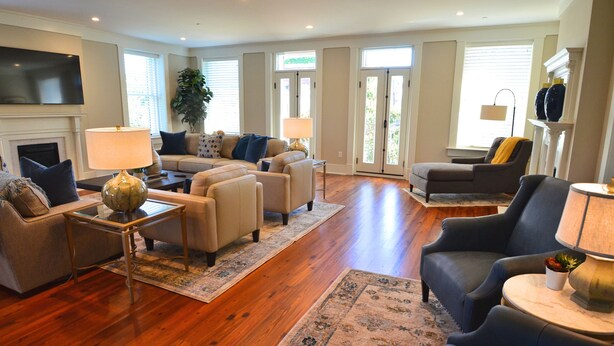 A spacious living room with hardwood flooring, a fireplace, a television, and multiple seating areas. - The Brigham 5 Star! ROOFTOP TERRACE Historic Savannah ULTIMATE LUX VACATION!! (Savannah)