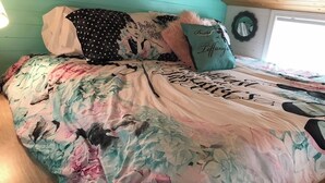 Ein Bett mit blumigem Bettzeug und einem Kopfkissen mit dem Aufdruck 'Lifelong Friends'.