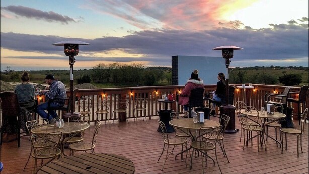 Eine Terrassengaststätte mit Tischen und Stühlen mit Blick auf eine schöne Landschaft.