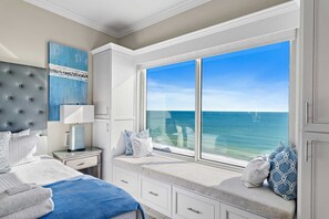 A bedroom with a large window overlooking the ocean, a bed with white bedding, a nightstand, and a dresser. - Updated Leeward Key 1005, 2 bed/2 Bath, Beach Service beautiful condo (Miramar Beach)