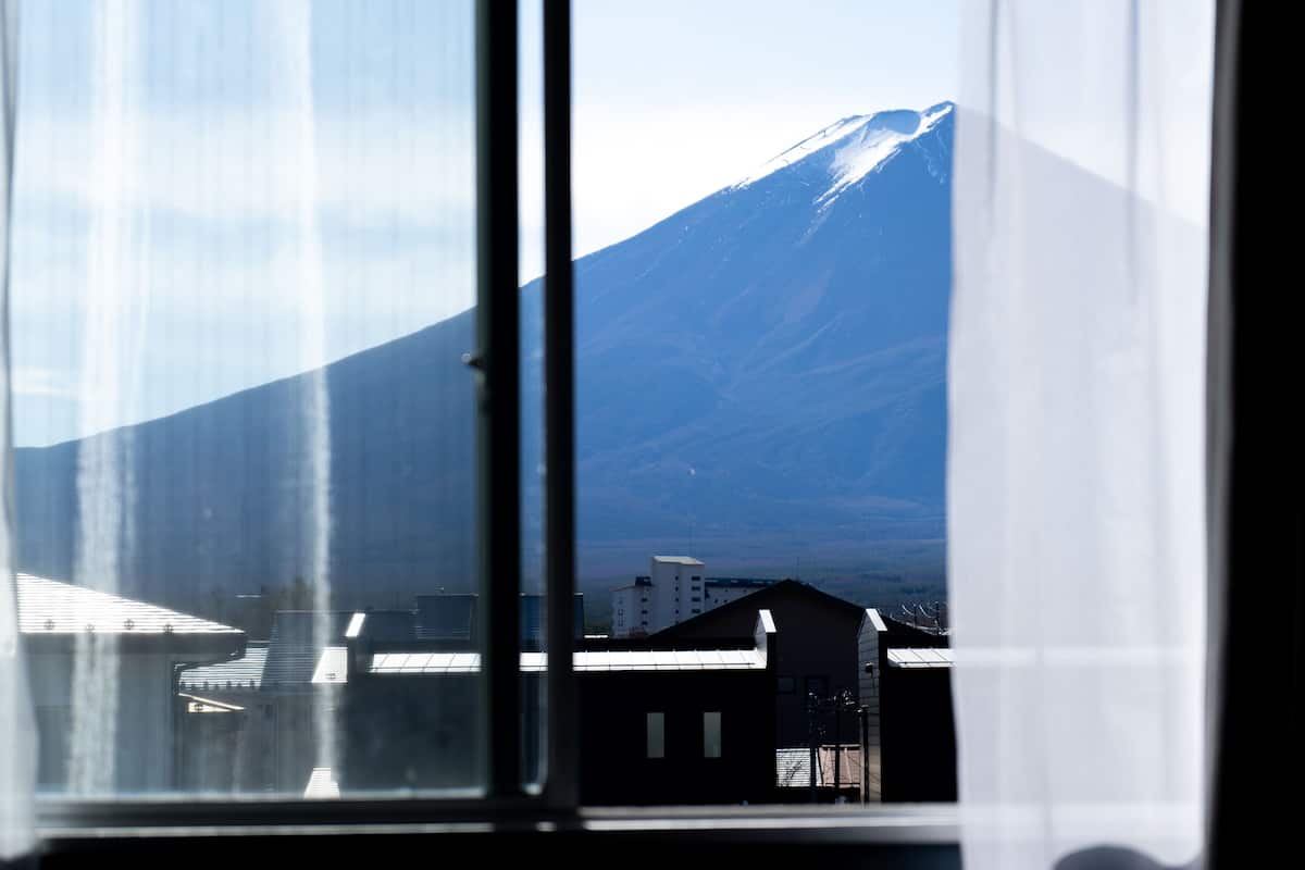 A view through a window of a building with a mountain in the background.