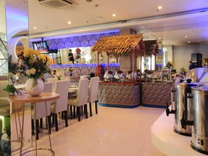 Un restaurante con barra, mesas y un espacio para buffet.