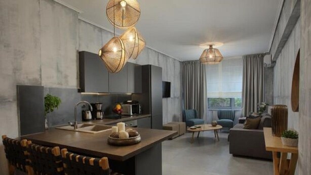 A modern kitchen with a central island, dining area with chairs, and a living room with a sofa and coffee table. - LeGeo-Luxurious Athenian Apartment (Athens)