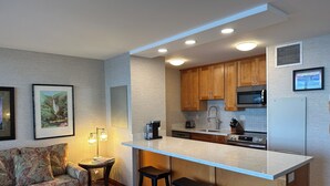 Une cuisine moderne avec des meubles en bois, un réfrigérateur en acier inoxydable et un four à micro-ondes encastré.