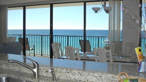 Cucina con una grande finestra vista mare, lavello e zona pranzo con sedie.