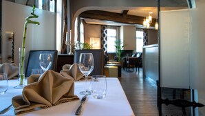Un coin repas avec une table dressée pour deux personnes, agrémenté d’un vase en verre transparent, d’une serviette pliée et d’un verre à vin.