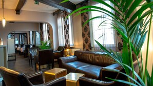 Un espace salon accueillant avec des canapés en cuir, des tables en bois et des plantes en pot.