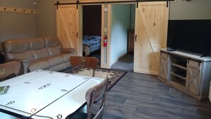 A cozy living room with a leather sofa, a dining table, and a mounted deer head. - HOCKING HILLS AREA LODGING. Adults/21 & Older Only Getaway. Smoke & Pet Free. (McArthur)