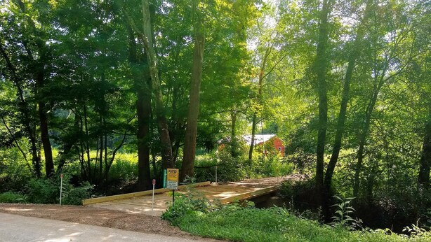 A paved path leading through a wooded area with a wooden bridge over a small stream. - HOCKING HILLS AREA LODGING. Adults/21 & Older Only Getaway. Smoke & Pet Free. (McArthur)