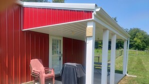 A red building with a covered porch, a door, and a chair. - HOCKING HILLS AREA LODGING. Adults/21 & Older Only Getaway. Smoke & Pet Free. (McArthur)