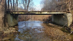 A concrete bridge over a small, rocky stream with bare trees in the background. - HOCKING HILLS AREA LODGING. Adults/21 & Older Only Getaway. Smoke & Pet Free. (McArthur)